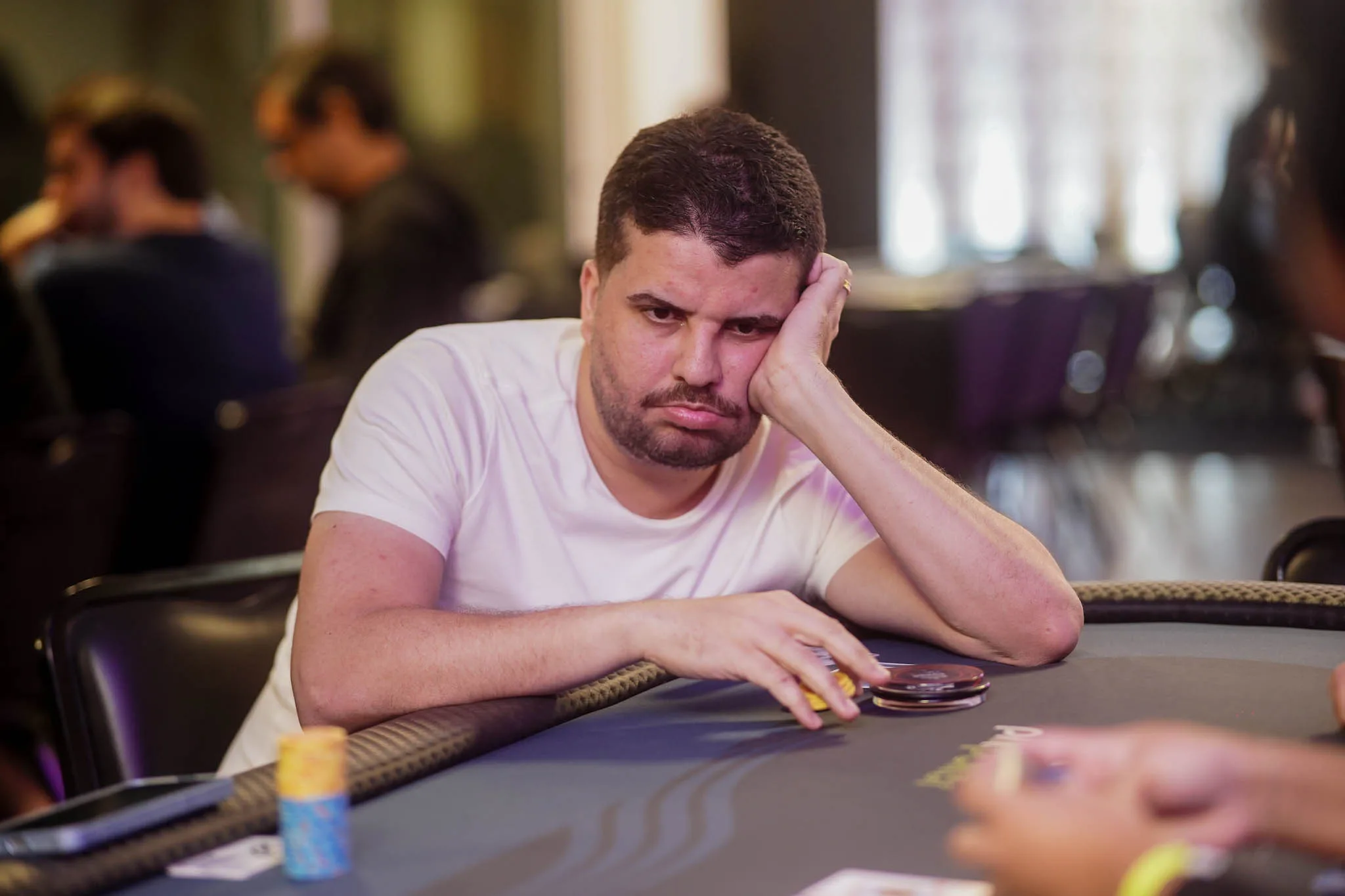 Two poker players smiling and shaking hands at a poker table with chips and cards, after a playful elimination