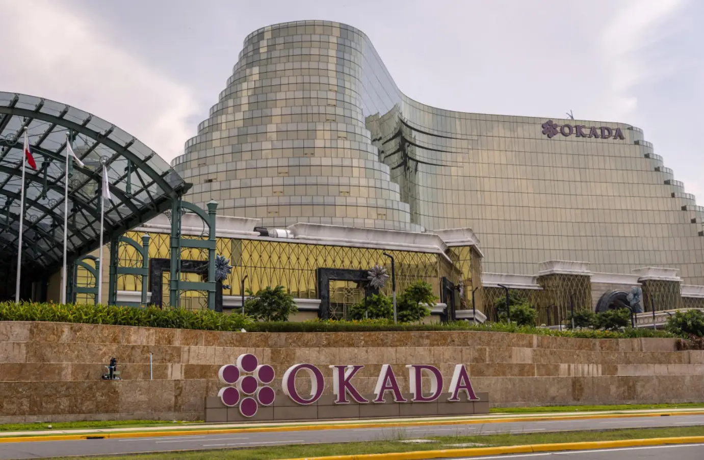 Exterior view of Okada Manila casino resort with a vibrant casino floor in the foreground