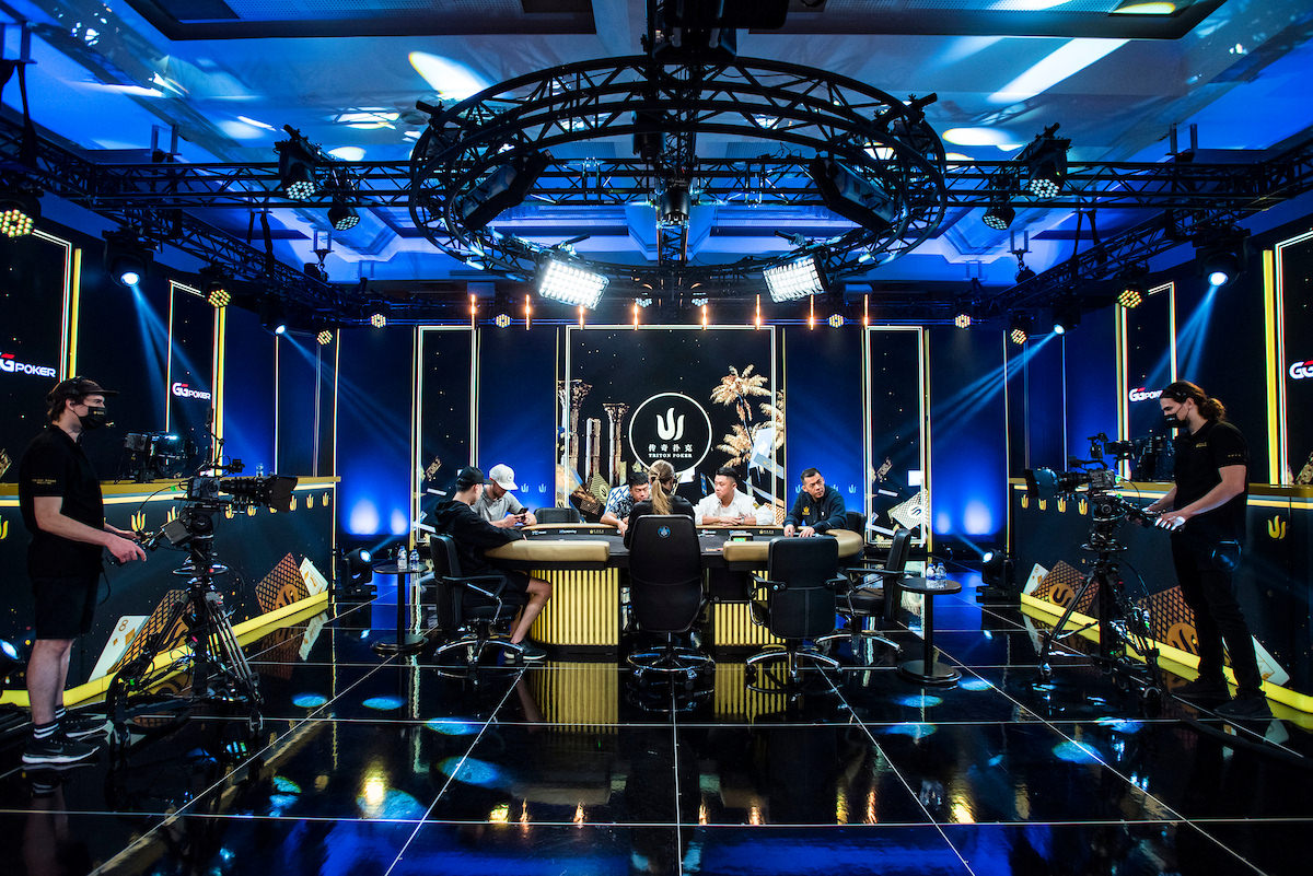 A high-stakes poker tournament table with players, a dealer, and stacks of chips, set up for a live broadcast at the Triton Poker Super High Roller Series in Montenegro.
