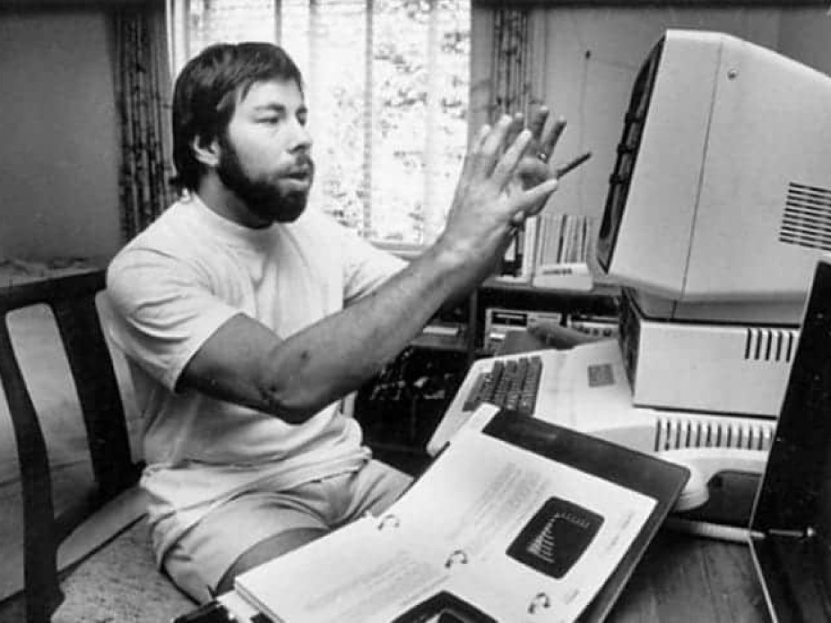 Steve Wozniak on stage at a graduation ceremony, addressing an audience with a smile.