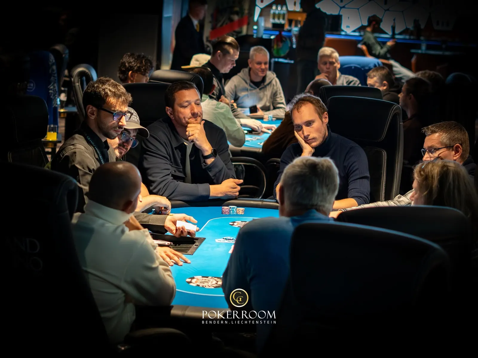 A poker tournament in progress at Grand Casino Liechtenstein, with players at the tables and chips on display.