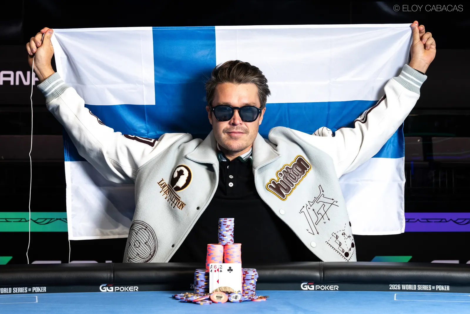 Eelis Parssinen holding his WSOP bracelet and a large check.