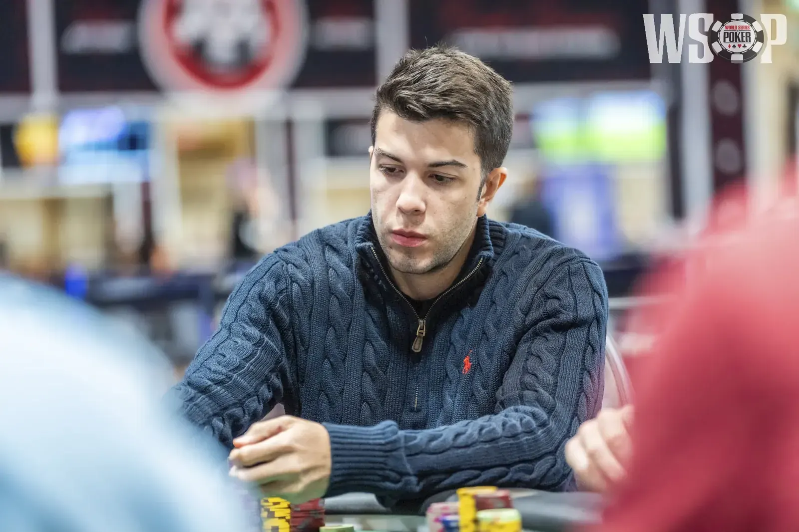 Professional poker players competing at a table during the World Series of Poker $25,000 High Roller Pot-Limit Omaha event.
