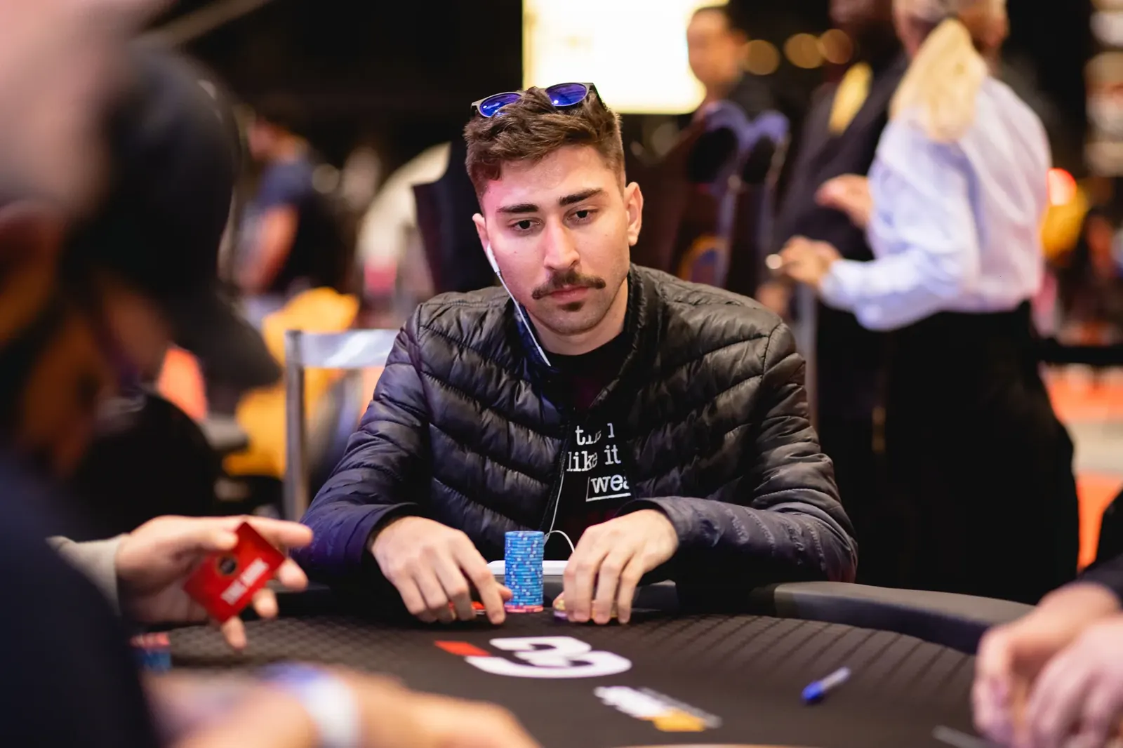 A diverse group of poker players at a final table during an online poker tournament, with virtual chip stacks displayed.