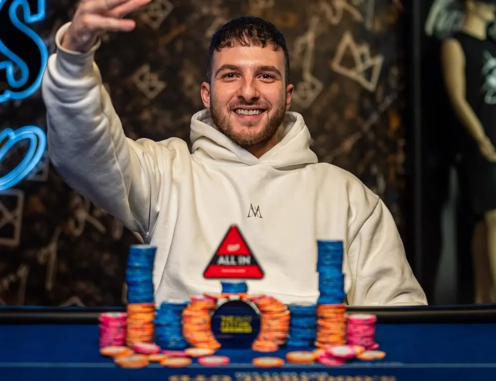 A poker player holding up chips after winning a tournament.