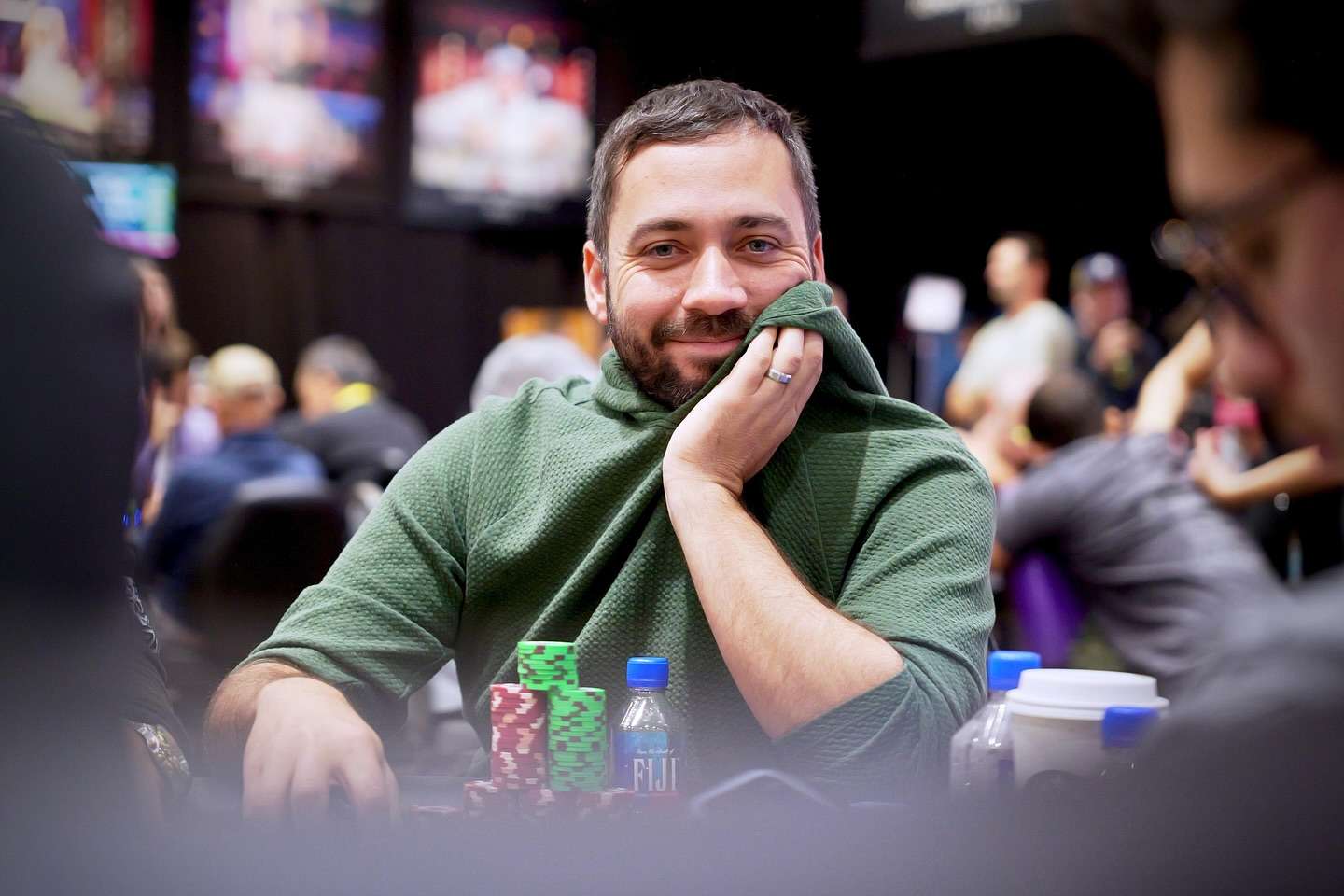Poker players at a World Series of Poker event, with one player looking focused at their chips.