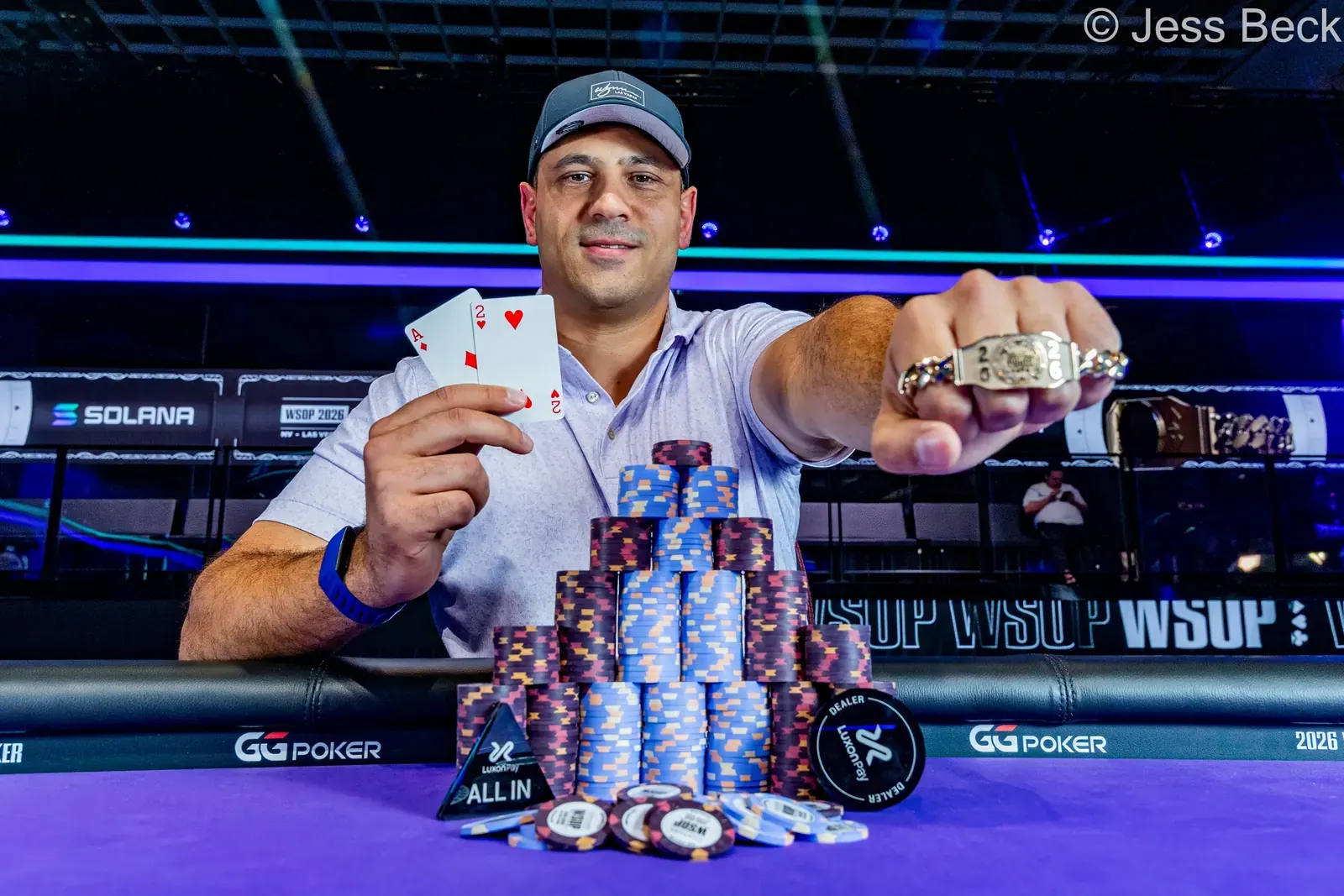 Omar Zazay smiling and holding his World Series of Poker bracelet.