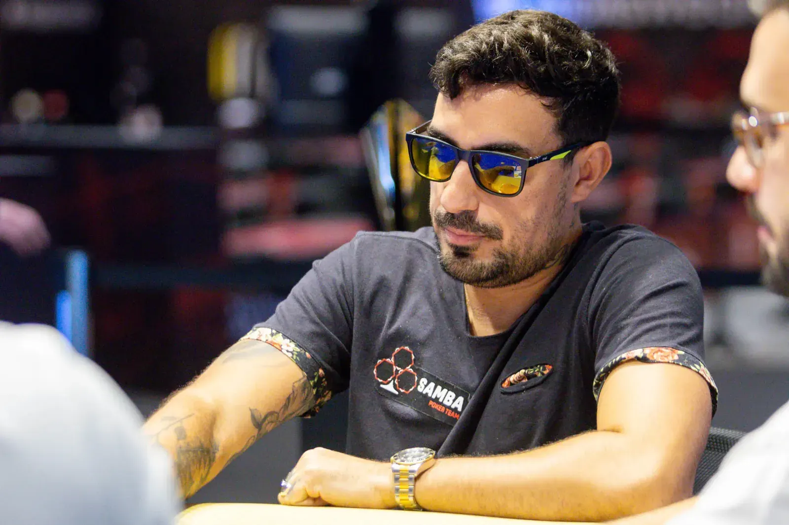 A poker player at a WSOP Main Event table, with chips and cards visible.
