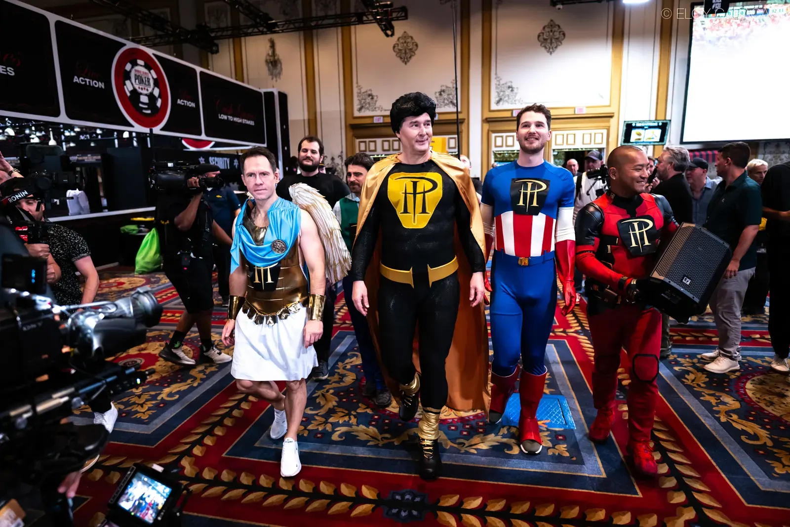 Phil Hellmuth in a custom superhero costume, posing with other characters at the entrance of the 2026 World Series of Poker Main Event.
