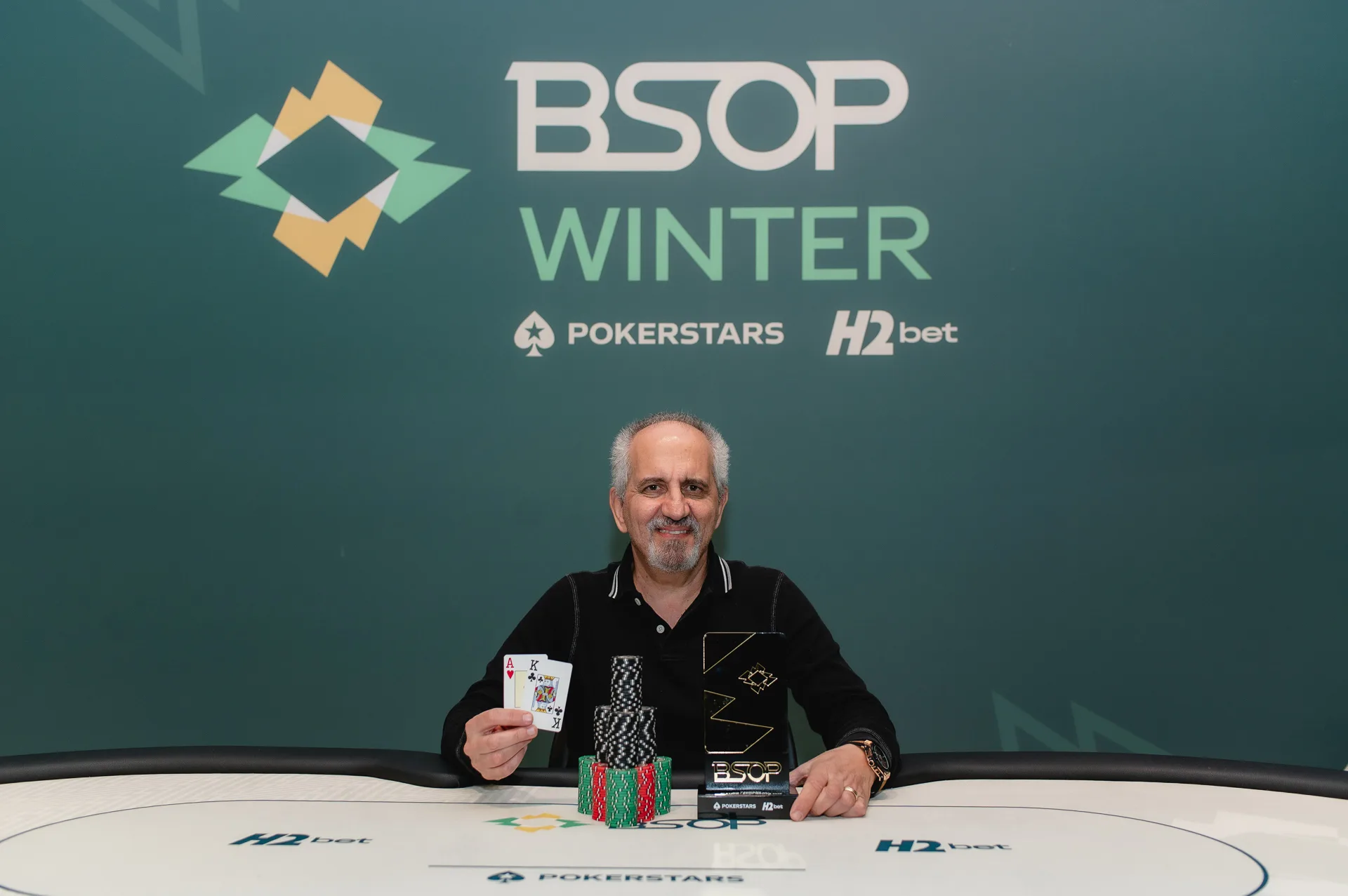 Ramiro Araújo celebrating his victory in the BSOP Winter Seniors tournament, holding a trophy and a check